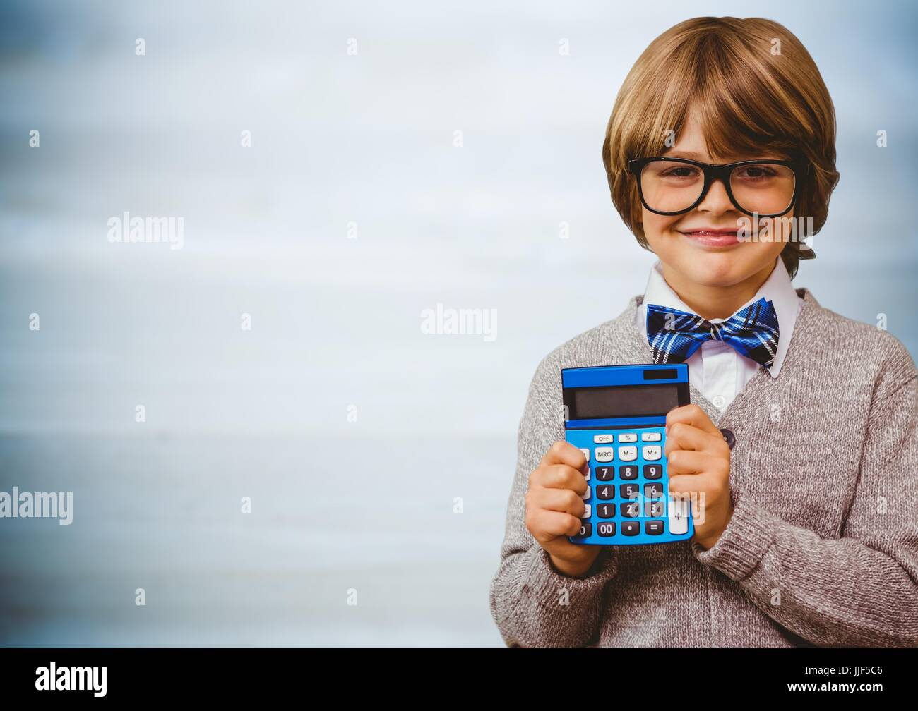 Digital composite of Boy smiling with calculator against blurry blue ...