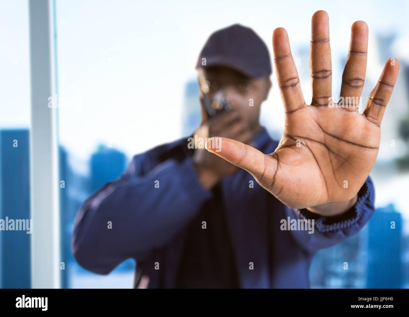 Digital composite of Security guard with walkie talkie and hand in front against blurry window showing city Stock Photo