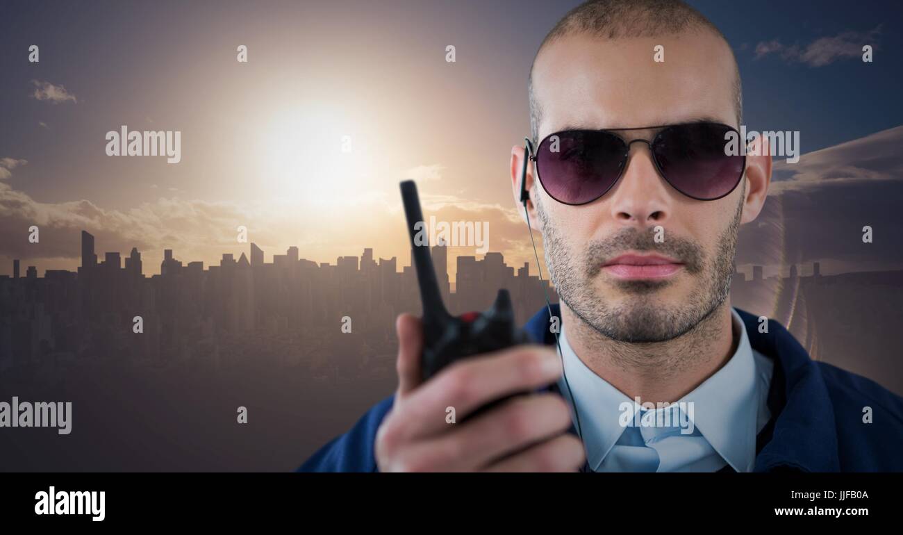 Digital composite of Security guard with walkie talkie against skyline and sunset Stock Photo