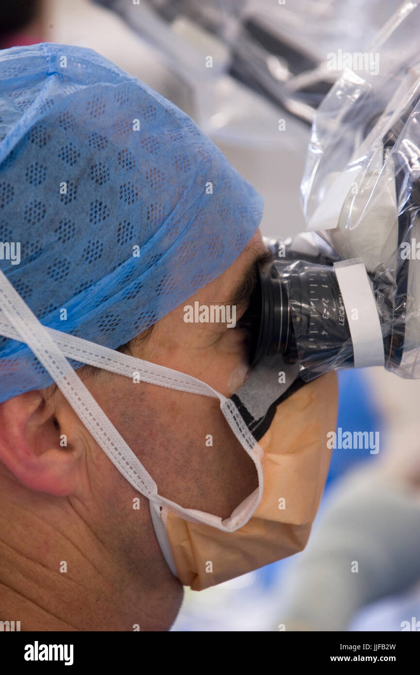 Surgeon uses microscope to work on implantation of internal part of a binaural cochlear receiver for patient with severe hearing difficulties Photogra Stock Photo