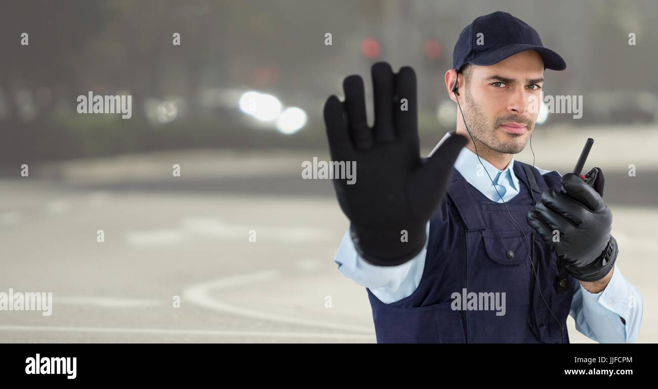 Digital composite of Security guard with walkie talkie and hand up against blurry street Stock Photo