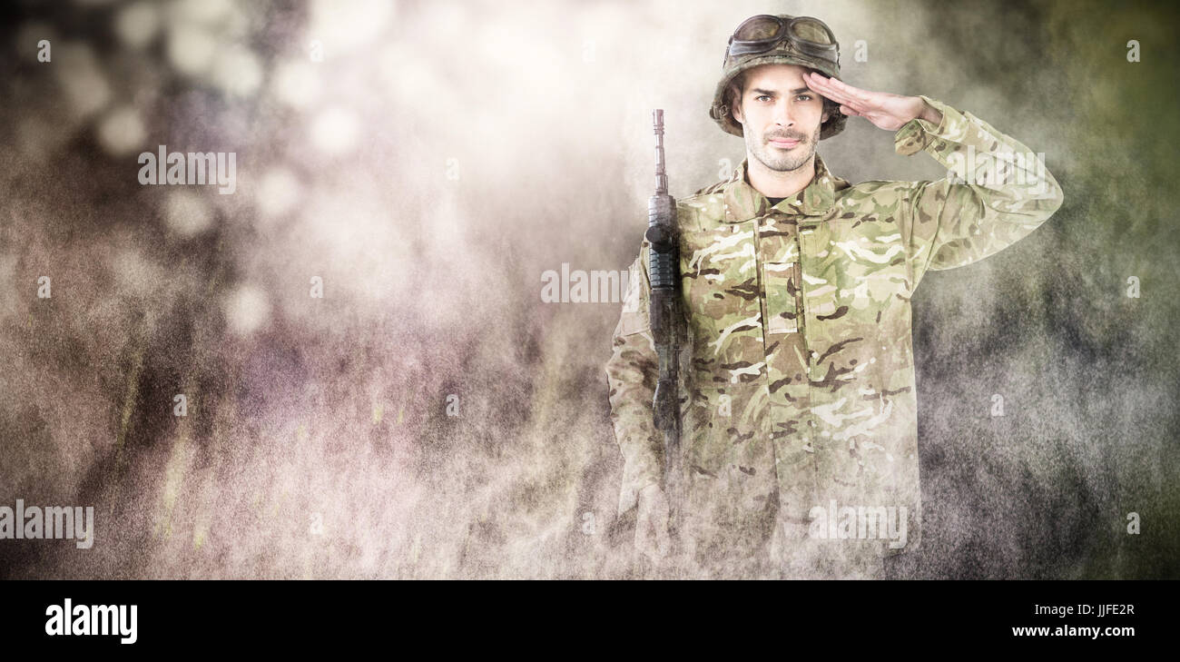 Portrait of soldier holding rifle and saluting against dark background ...