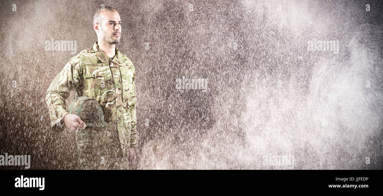 Confident soldier holding helmet while standing against black Stock ...