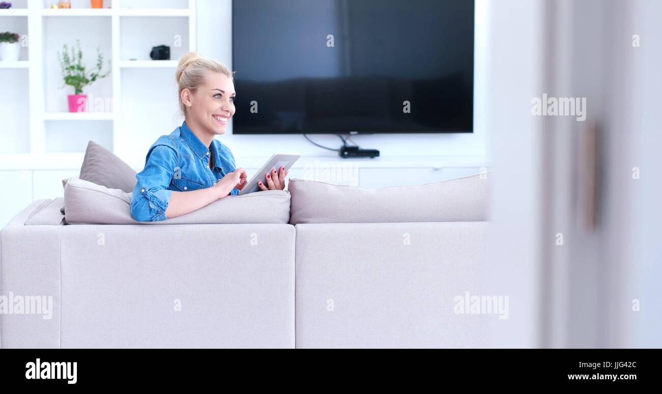 young happy woman on sofa using tablet computer at luxury home Stock ...