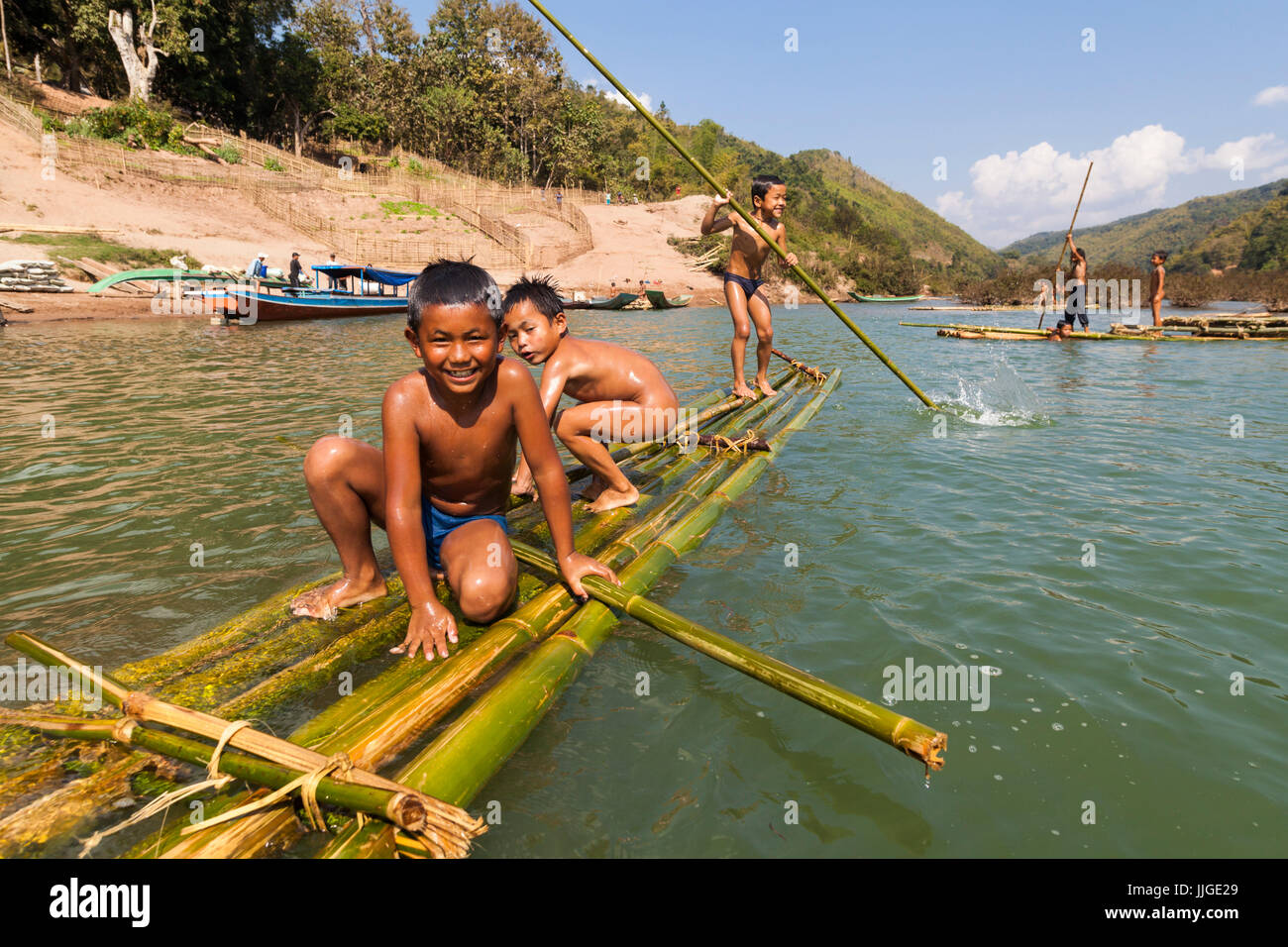 Children play in the Nam Ou River on bamboo rafts at Ban Hat Kham, Laos. The village would be completely inundated by proposed Dam #3 (whose construction has not yet commenced). Stock Photo