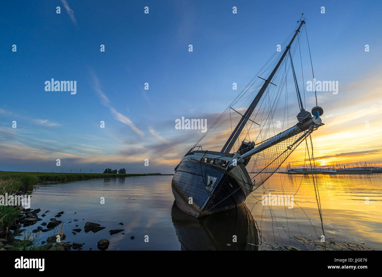 Scenic sunset at a stranded sailing boat near Lemmer, the Netherlands Stock Photo