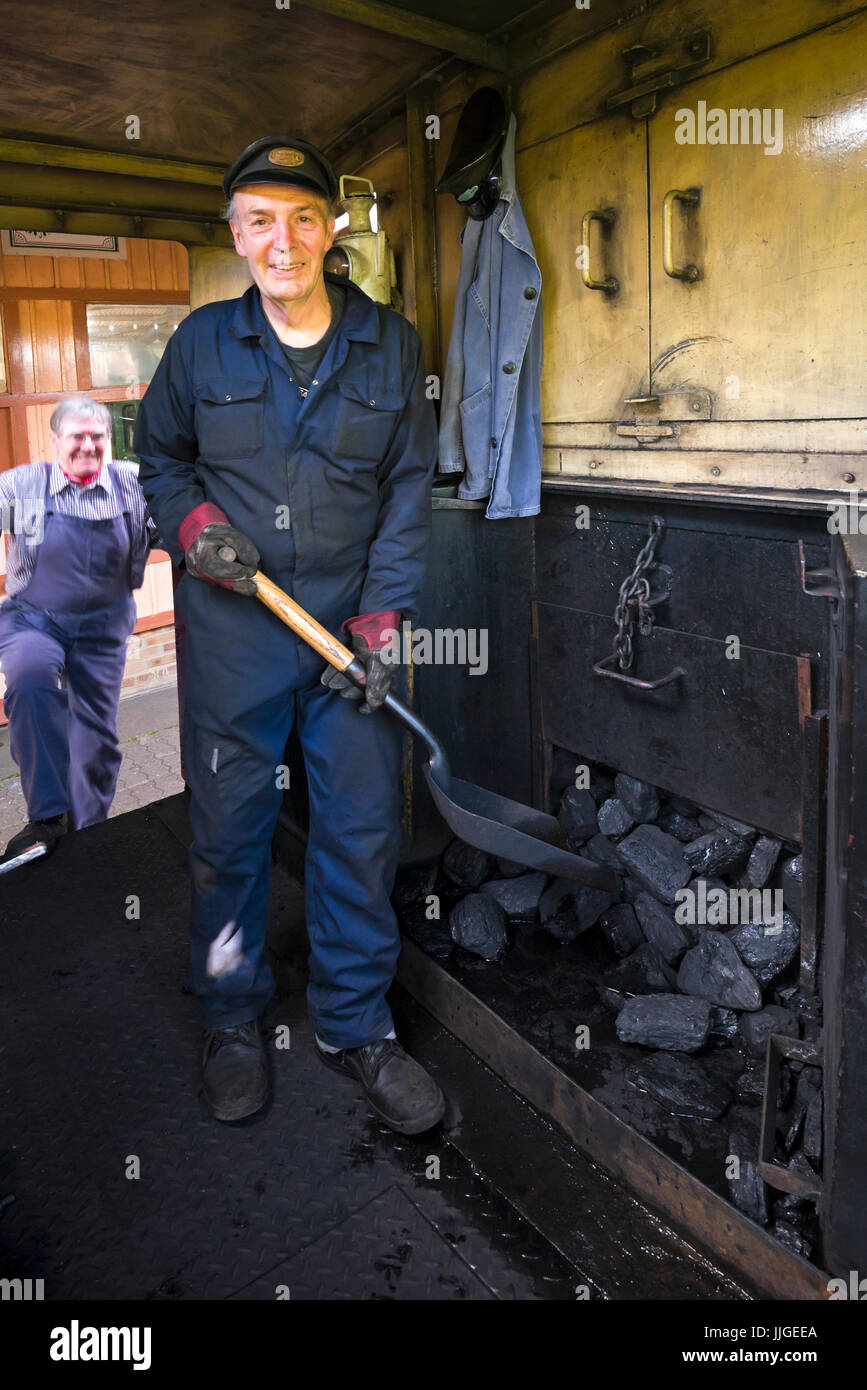 Vertical portrait of a fireman standing on the footplate of a steam locomotive. Stock Photo