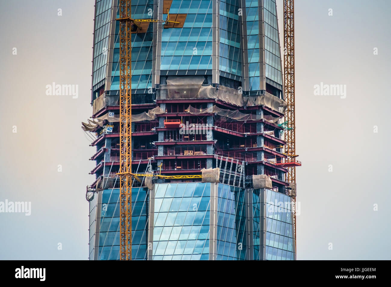 Skyscraper In Construction Detailed view of a skyscraper under construction with the cranes on the ...