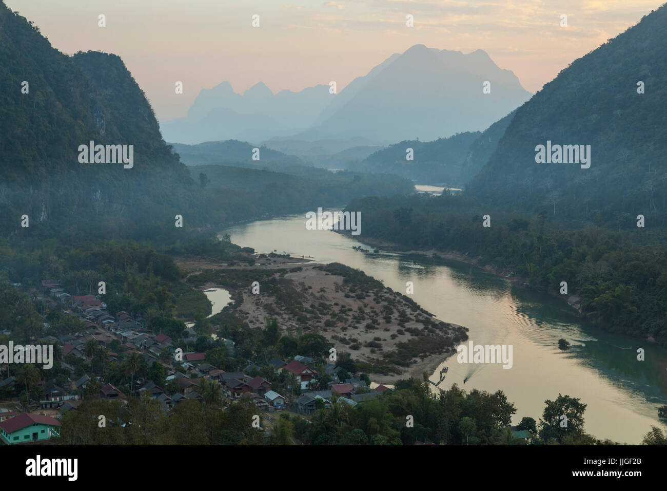 A boat motors into port at Muang Ngoi, Laos, a town on the Nam Ou River set in a spectacular karst landscape. Stock Photo