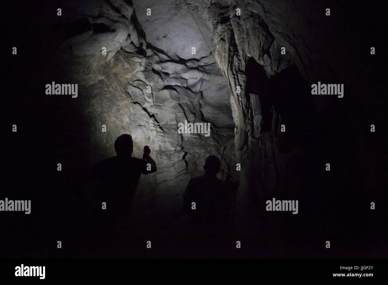 Jan (left) and Robert Hahn look out for bats as they explore a natural limestone cave used by past residents of Muang Ngoi, Laos as a bomb shelter during the U.S. bombing raids of the Secret War. Stock Photo
