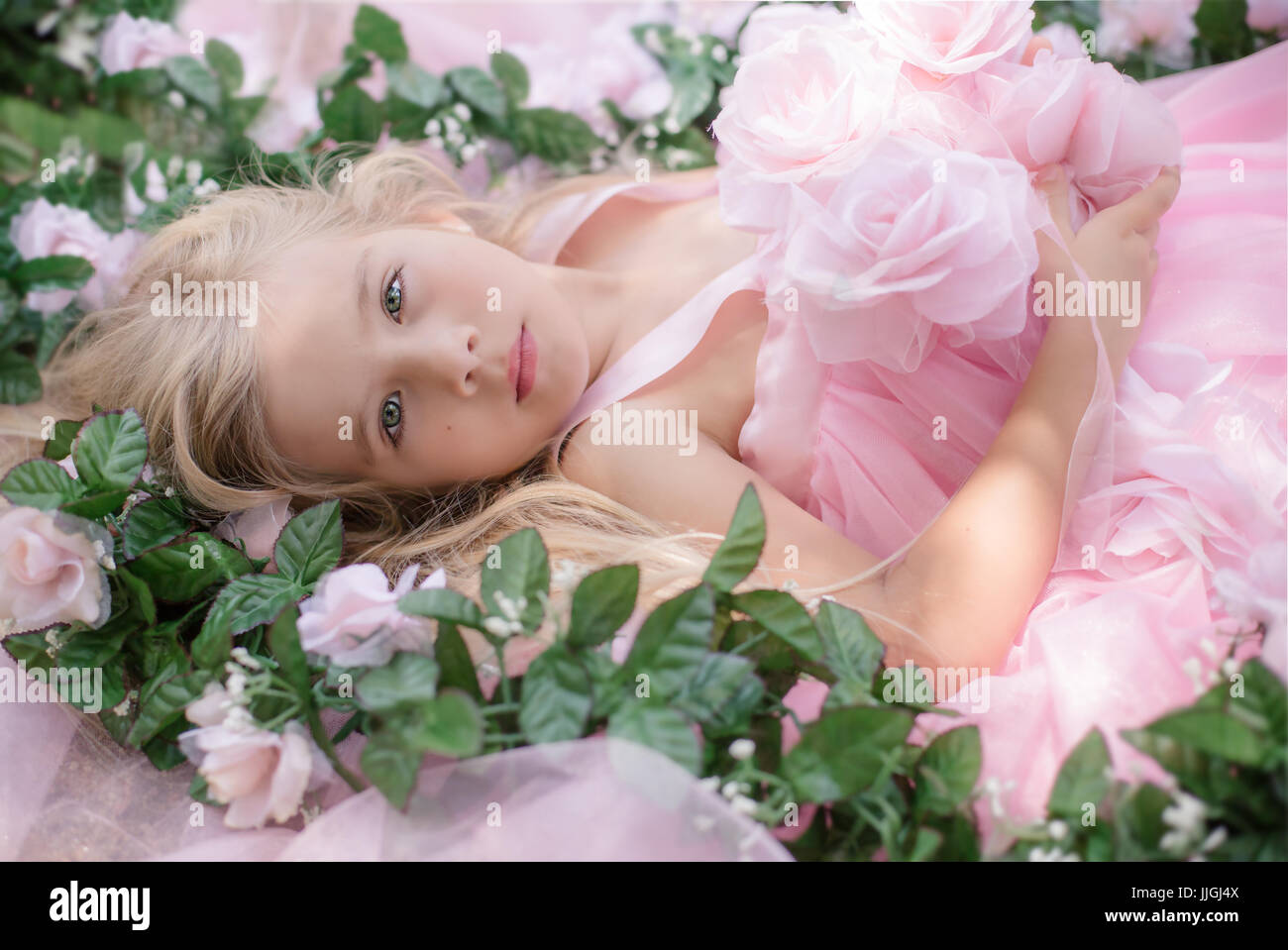 Girl in a vintage dress with roses lying amongst flowers, California, USA Stock Photo