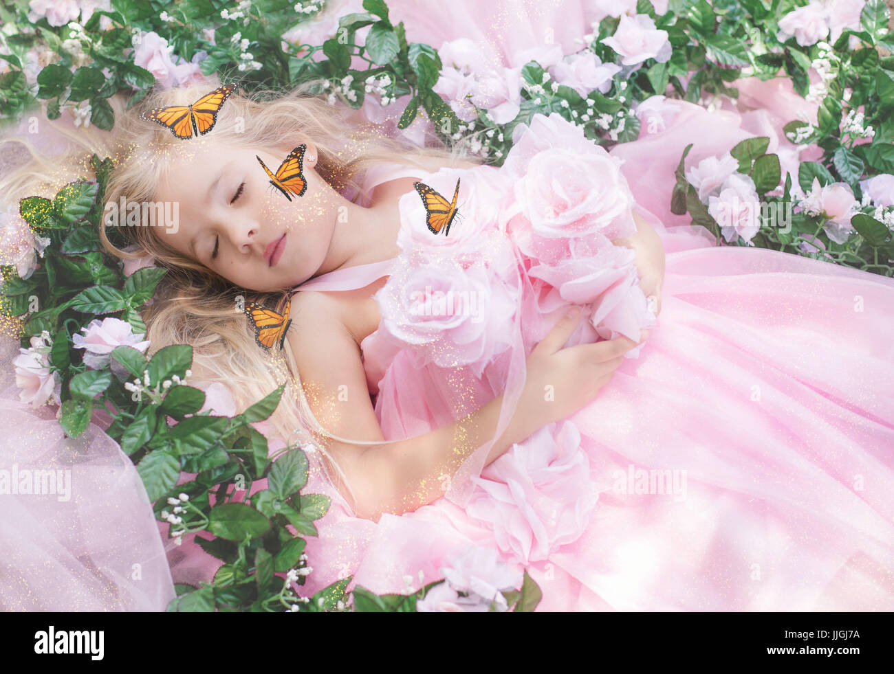 Girl lying amongst flowers sleeping with butterflies flying around her, California, USA Stock Photo