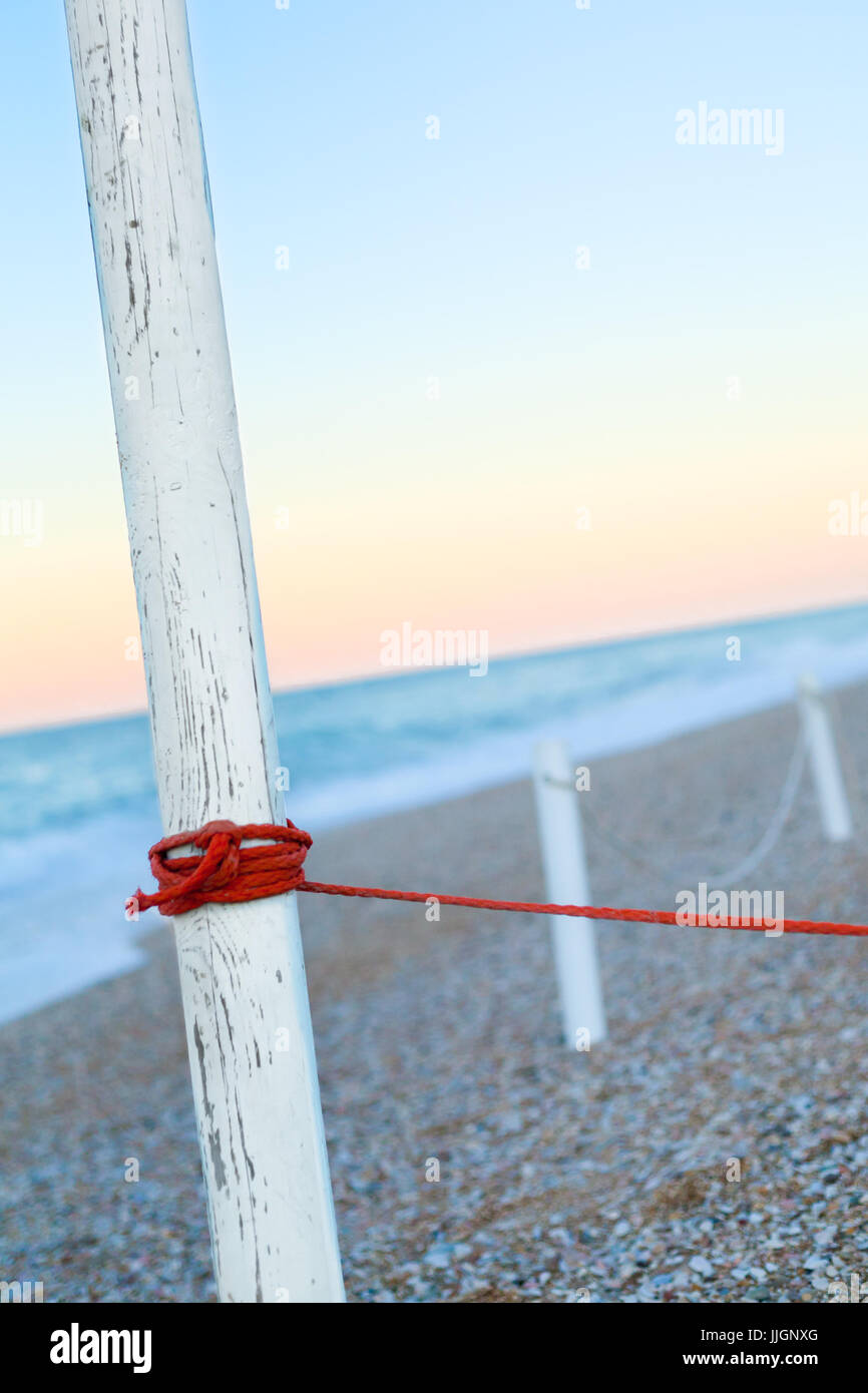 Red leash pole with Morning light stones on beach close to the shore on seaside Stock Photo