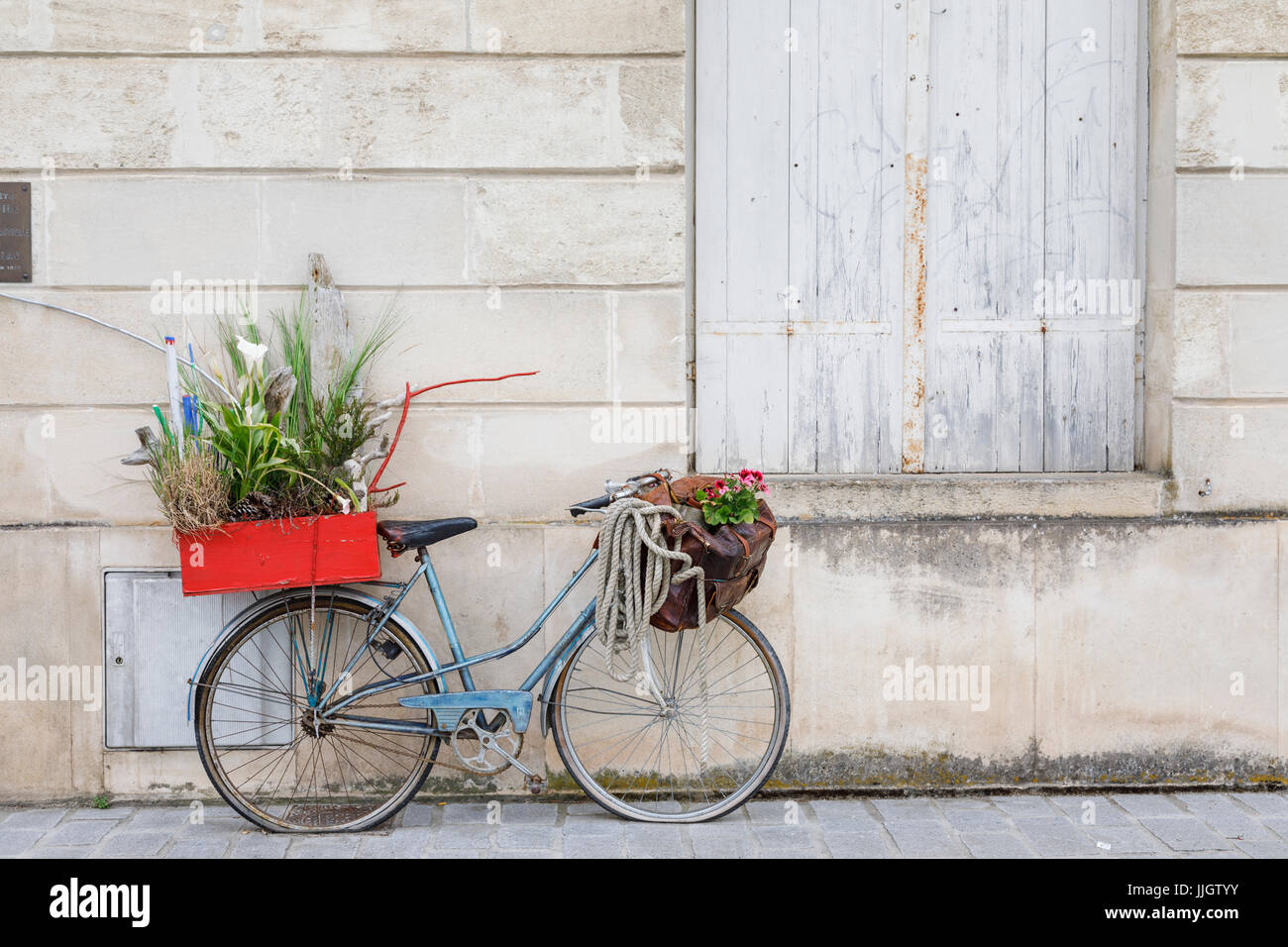 Old fashioned blue lady's bicycle with flat tyres parked leaning against a wall, Pauillac, Gironde department, Nouvelle-Aquitaine, southwestern France Stock Photo