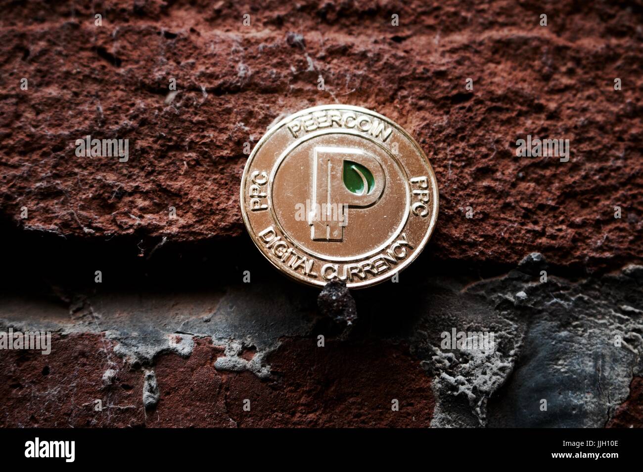 Cryptocurrency physical gold peercoin coin with green leaf in sign on black  brick wall Stock Photo - Alamy