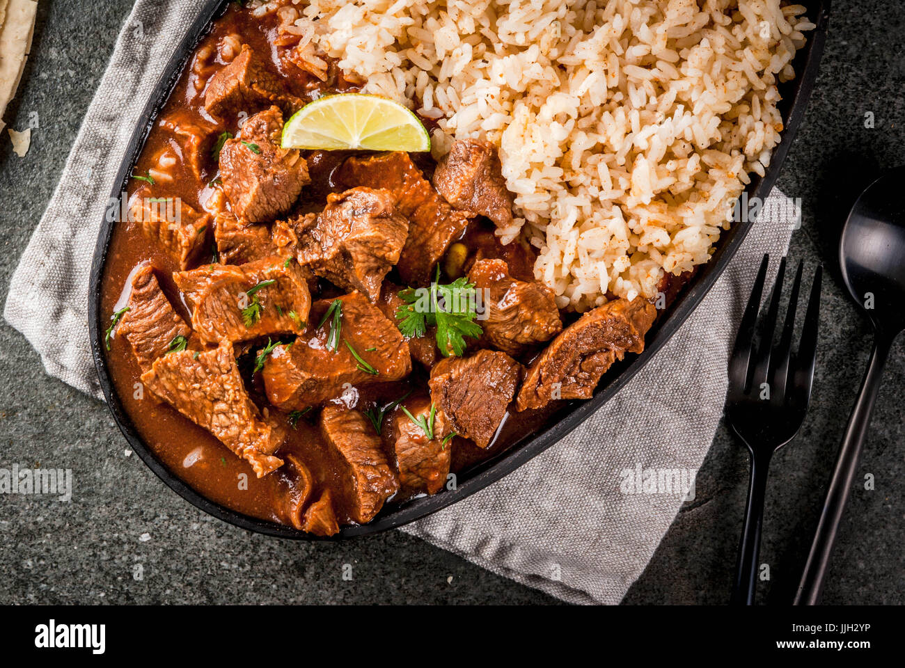 Mexican and American traditional food. Stew beef with tomatoes, spices, pepper - Chile Colorado. With boiled rice. lime, tortillas.  Copy space top vi Stock Photo