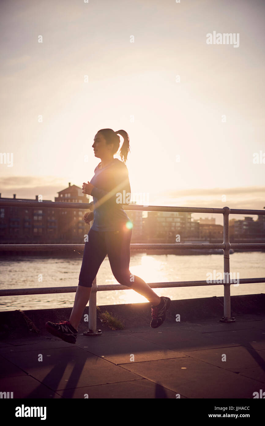 A woman running alongside the River Thames in London. Stock Photo