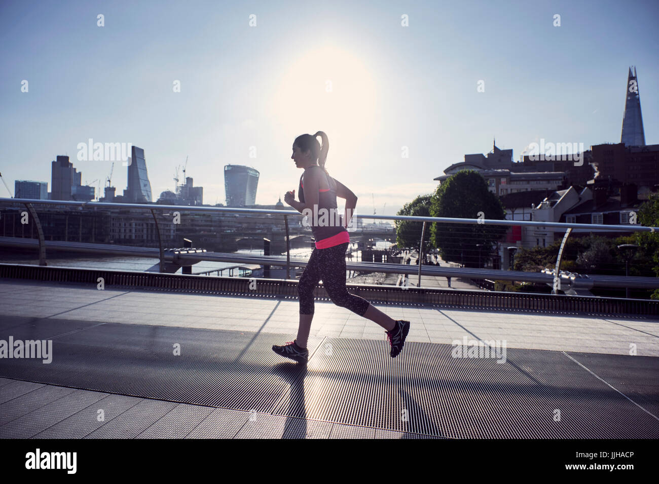 A woman running over the Millennium Bridge in London. Stock Photo