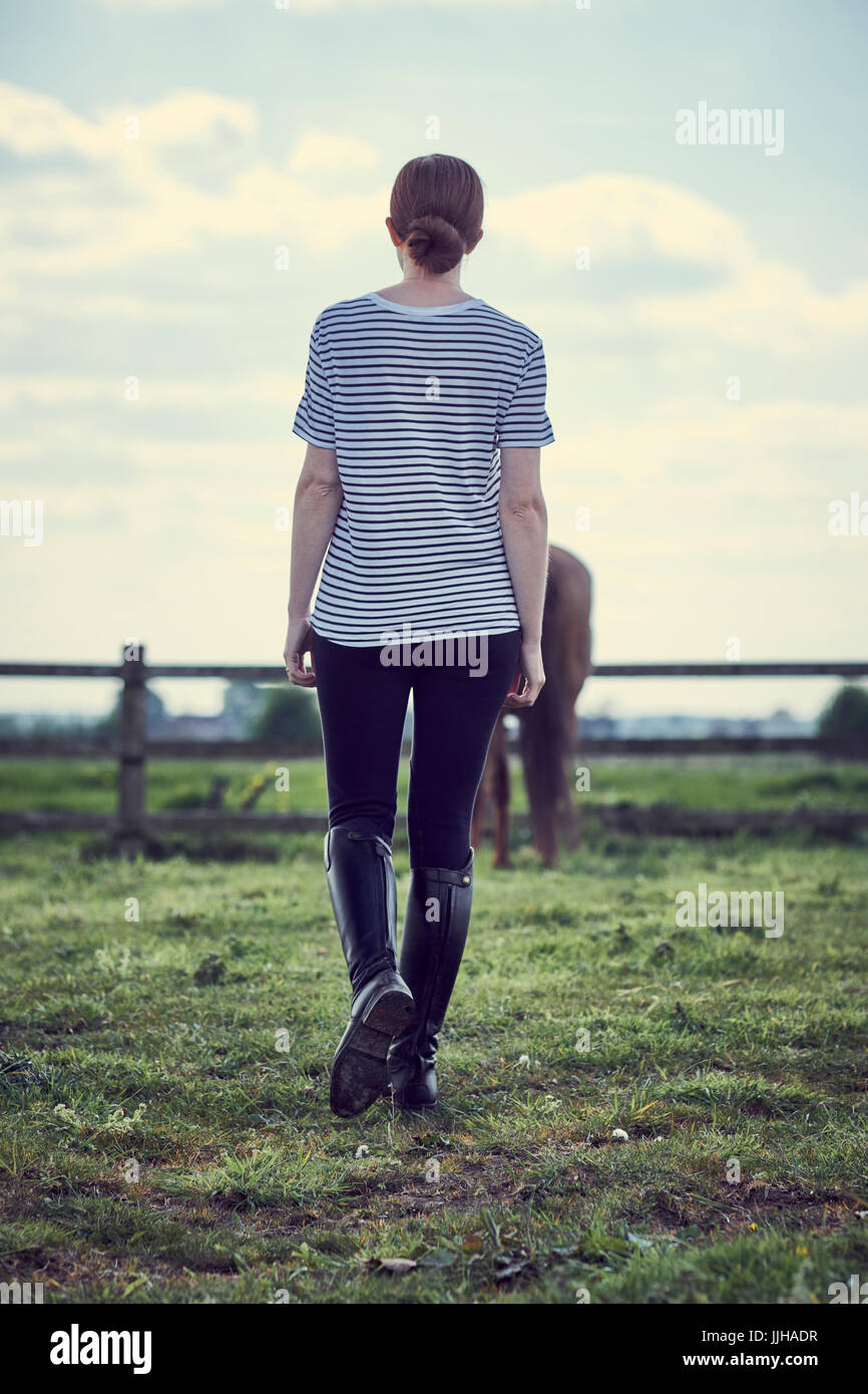 A young woman standing with her horse in a paddock. Stock Photo