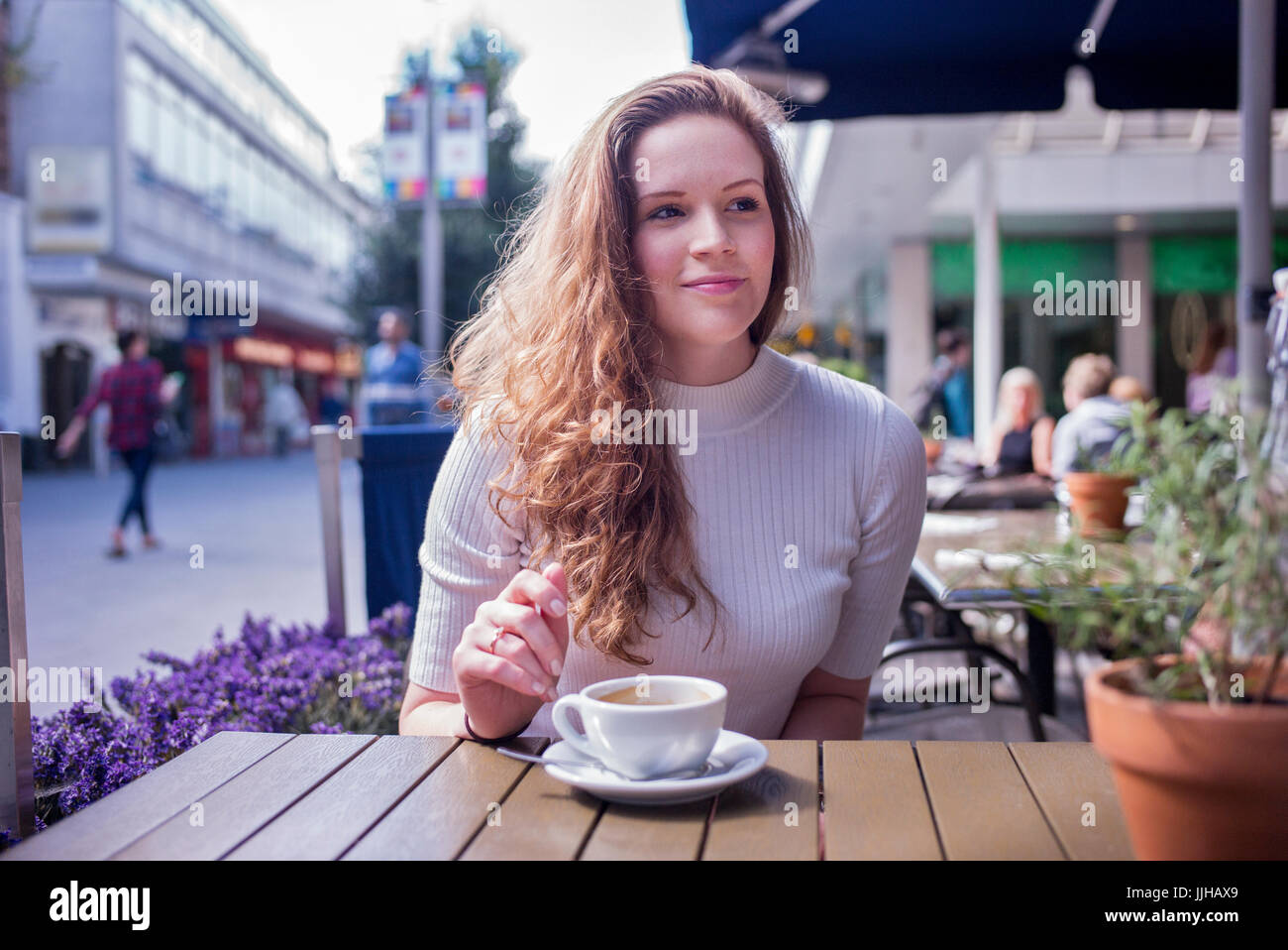 A young woman sitting outside a cafe. Stock Photo
