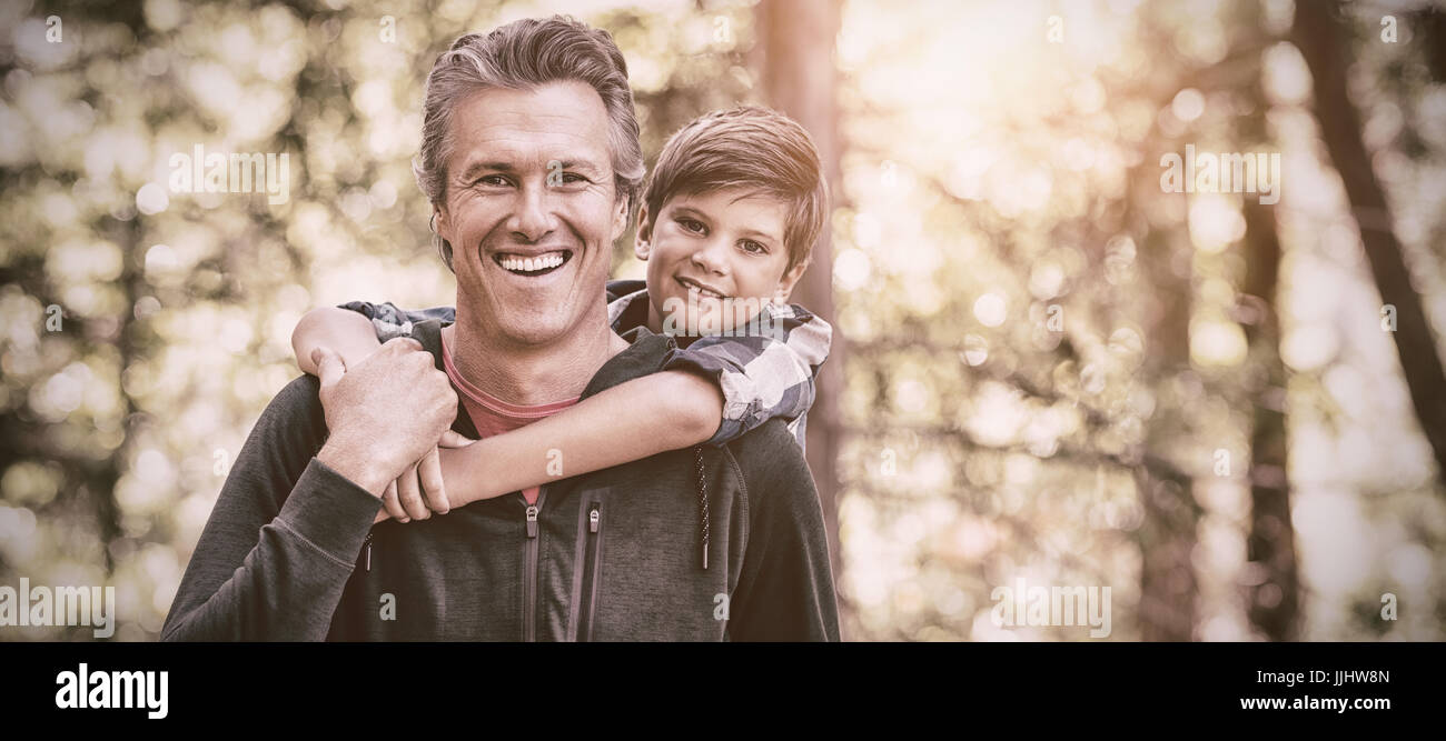 Portrait of happy father piggybacking son while hiking in forest Stock Photo