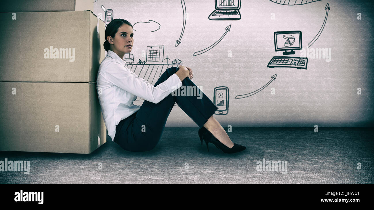 Businesswoman leaning on cardboard boxes against white background against grey room Stock Photo