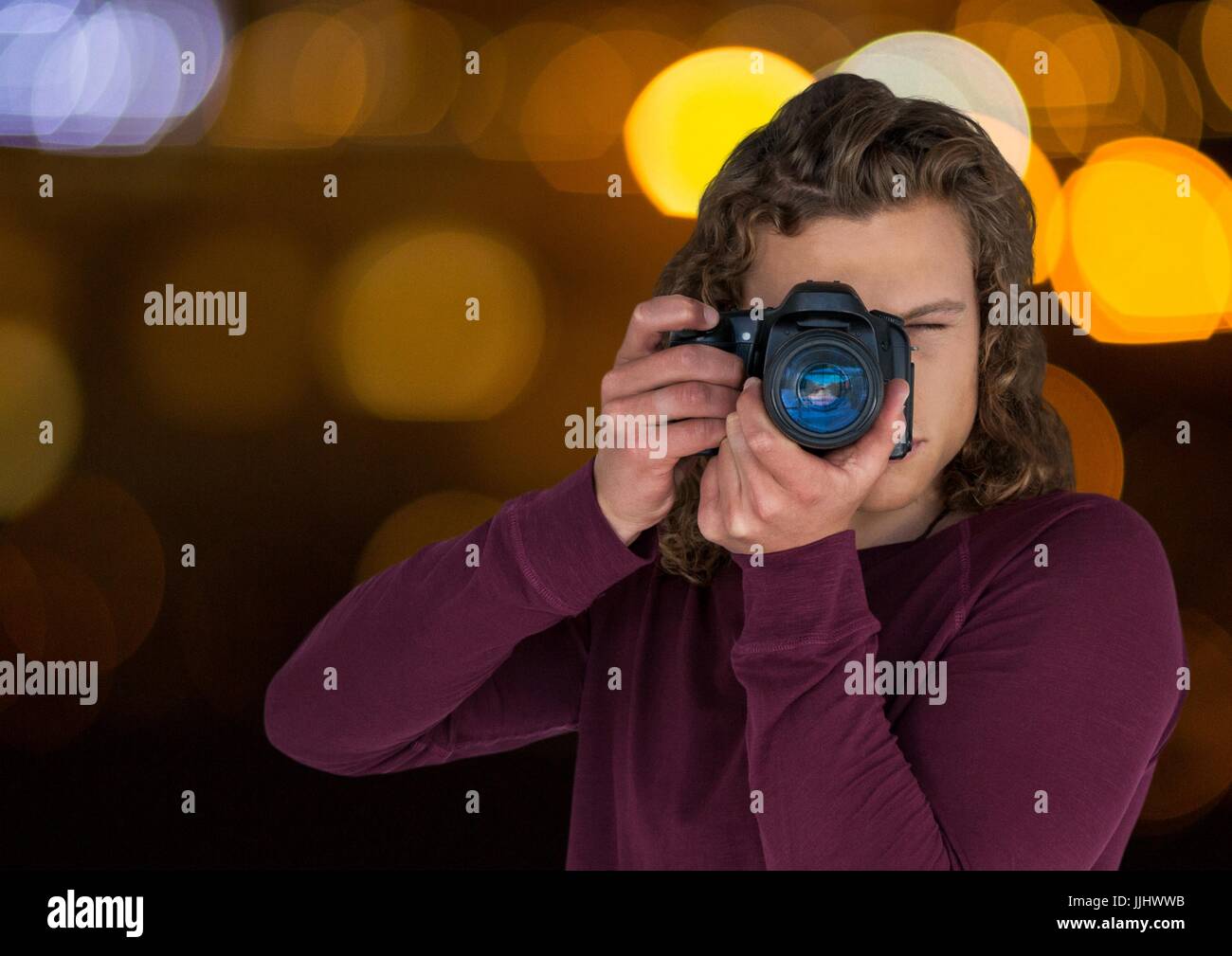 young hipster photographer taking a photo in the city at nights ( blurred lights) Stock Photo