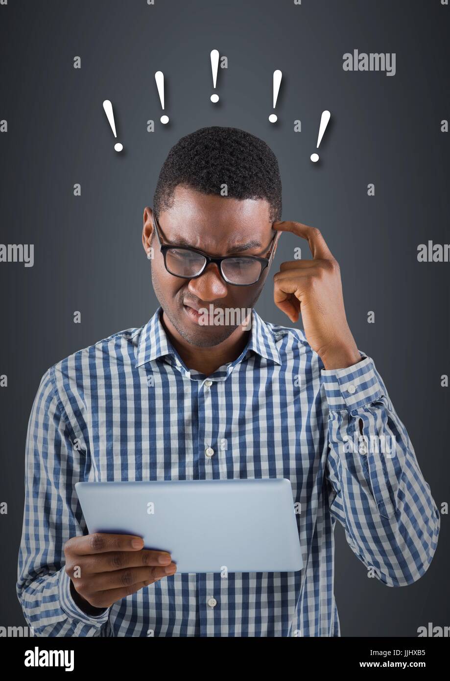 Frustrated business man with 3d tablet against blue background and exclamation points Stock Photo