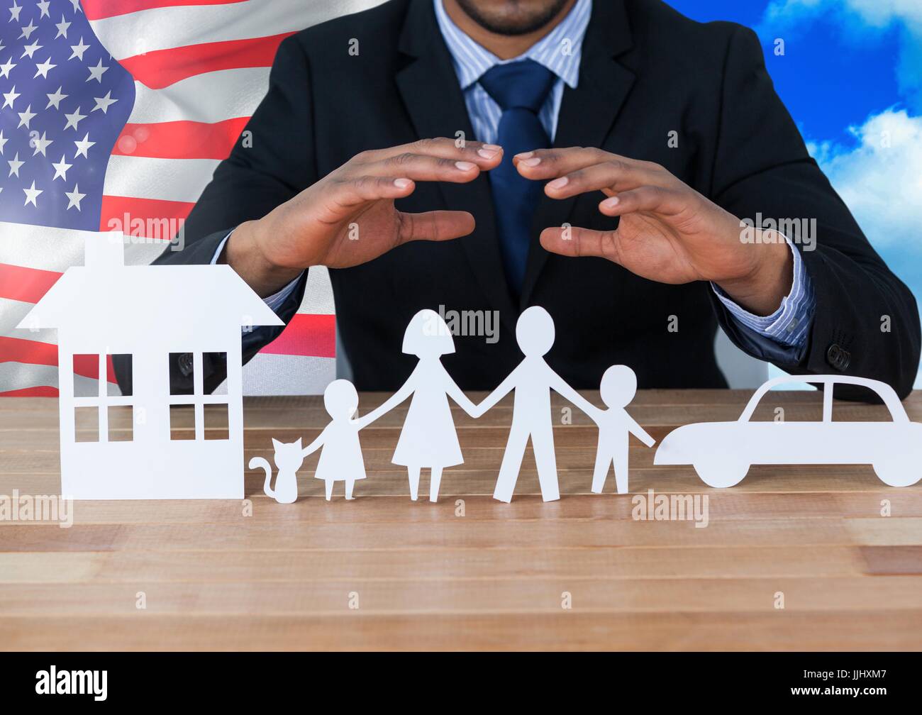 Business man showing 3D family, car and house on paper against american flag Stock Photo