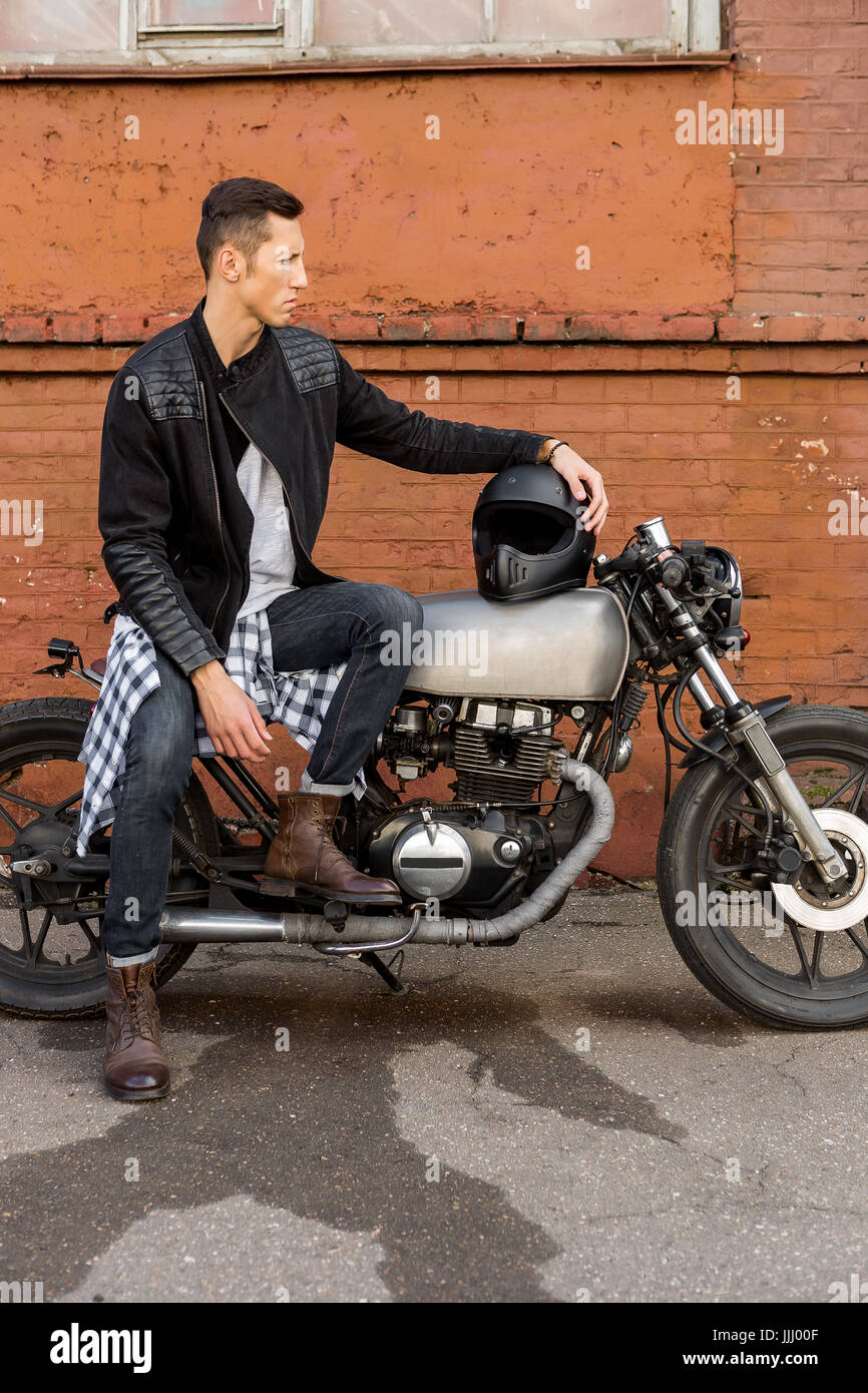 Handsome rider biker guy in leather jacket sit on classic style cafe racer motorcycle and hold hand on black helmet. Bike custom made in vintage garag Stock Photo - Alamy Handsome Rider Biker Guy In Leather Jacket Sit On Classic Style Cafe Racer Motorcycle And Hold Hand On Black Helmet. Bike Custom Made In Vintage Garag Stock Photo - Alamy