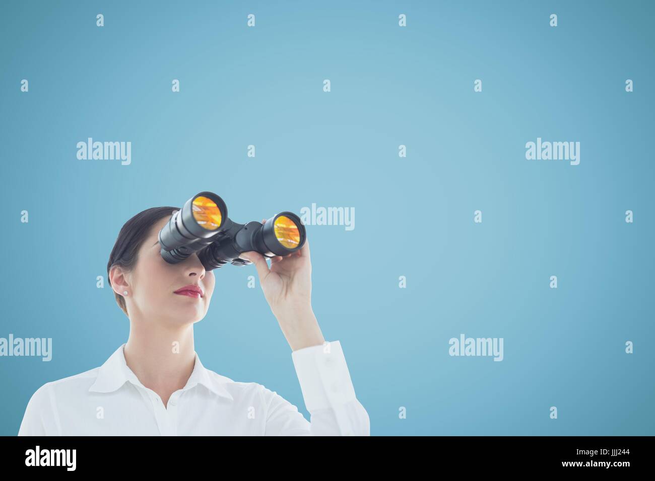 Woman looking through binoculars against blue background and copy space Stock Photo