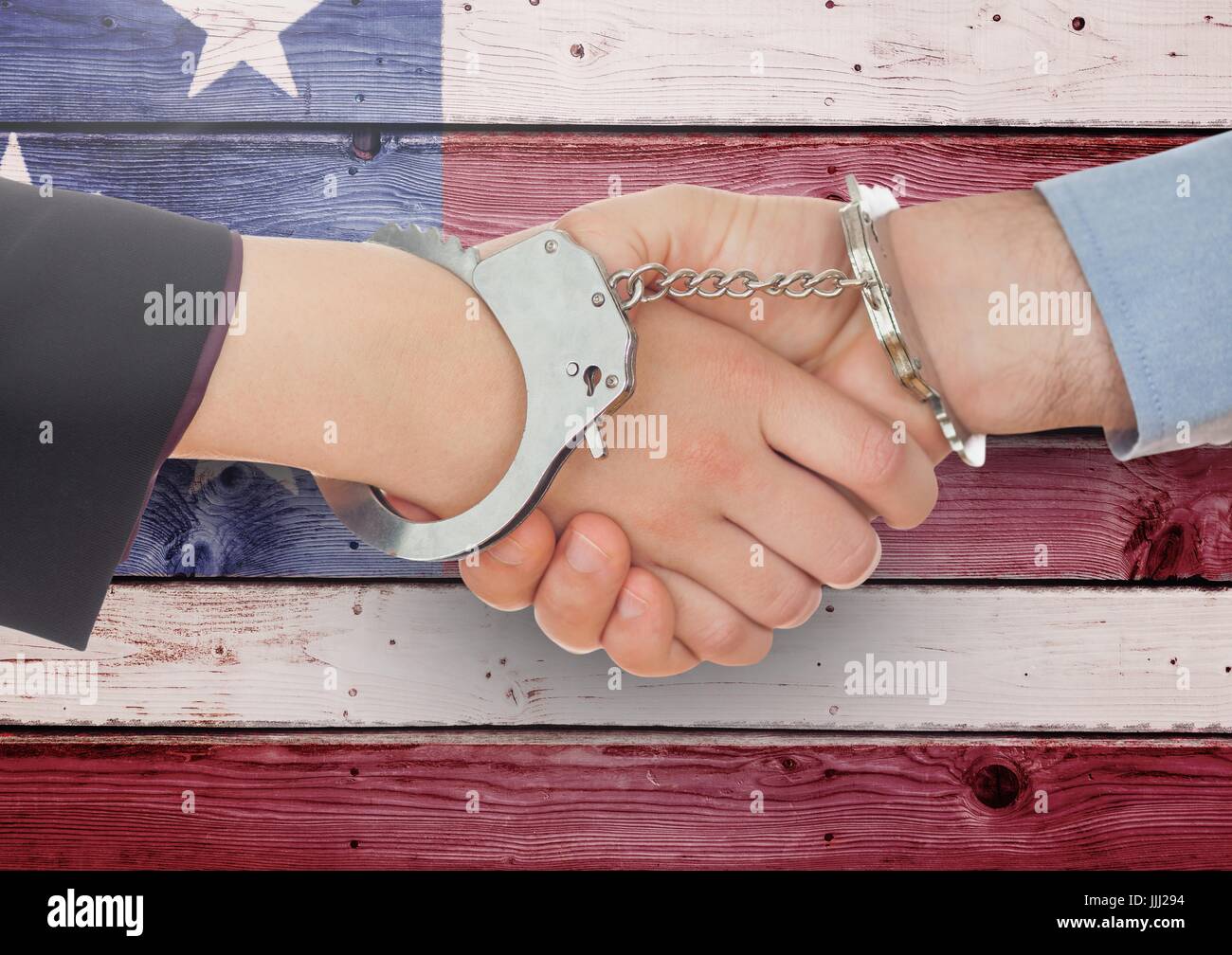 Handshake with handcuffs against wooden american flag background Stock Photo
