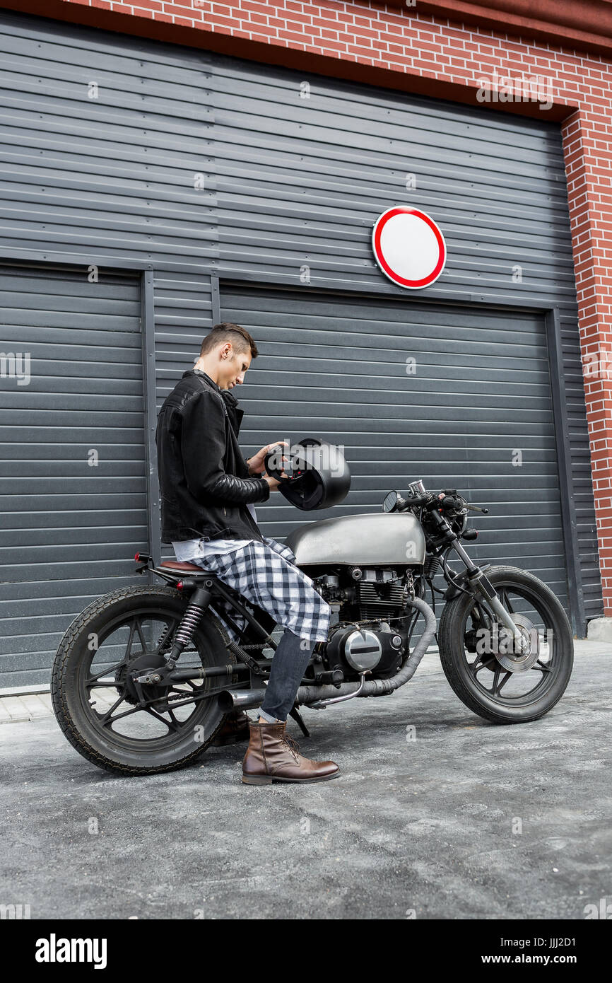 Handsome Rider Guy Put On Black Biker Helmet While Sit Classic Style Cafe Racer Motorcycle Near Industrial Gates Bike Custom Made In Vintage Garag
