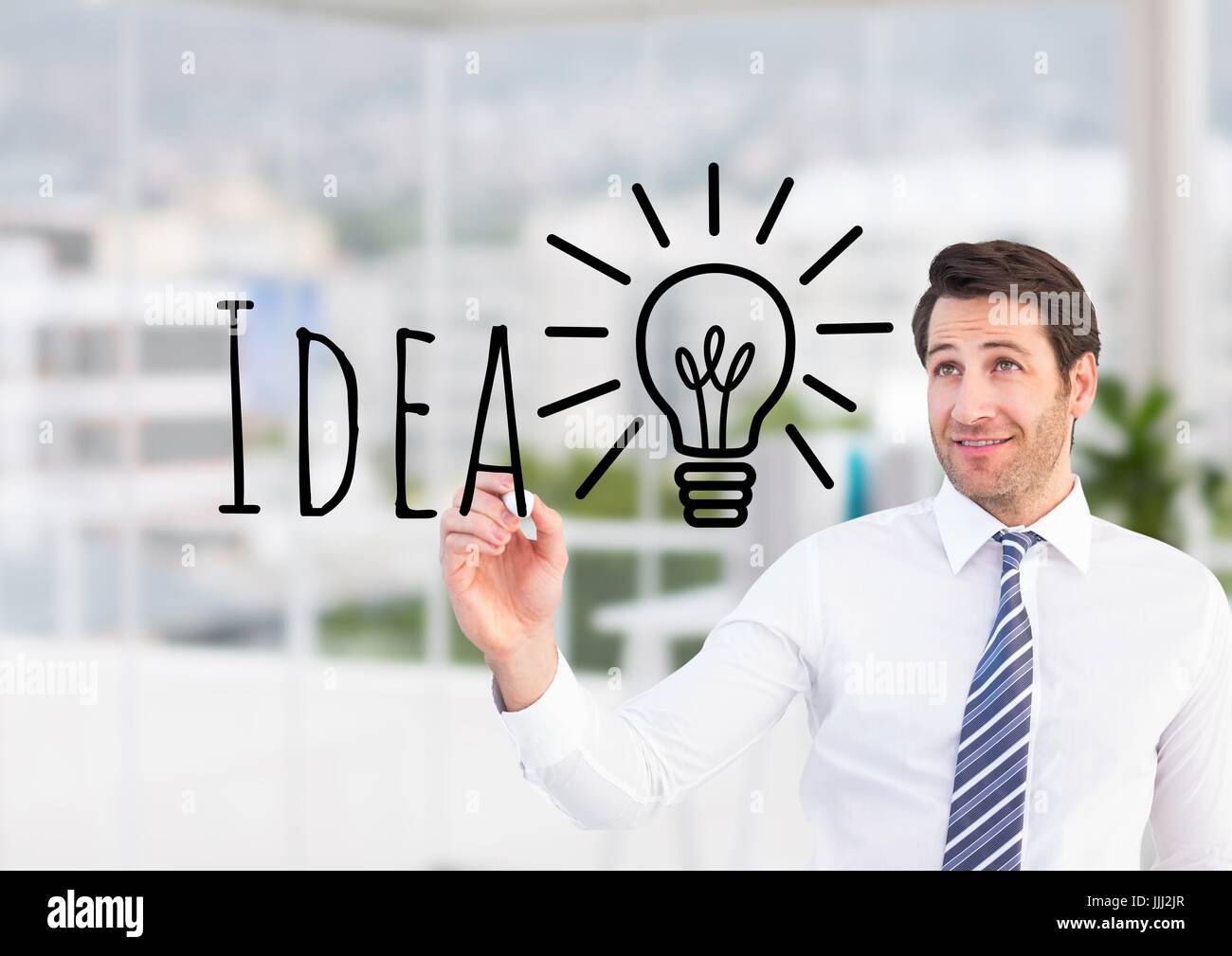 Businessman writing IDEA and drawing a light on the screen. He is in the office Stock Photo