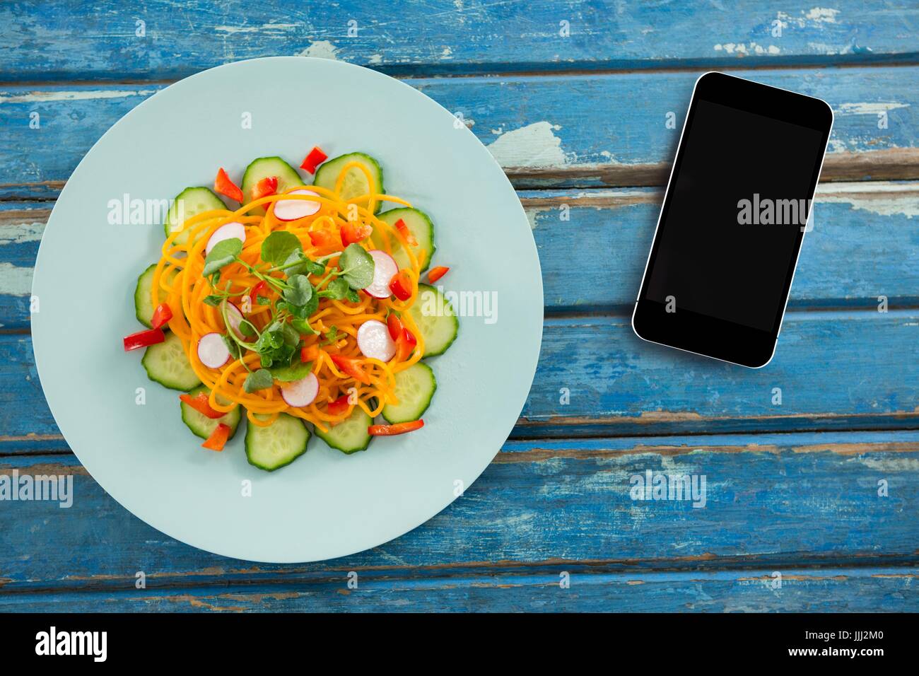 Phone on blue wooden desk with food and copy space on mobile phone Stock Photo