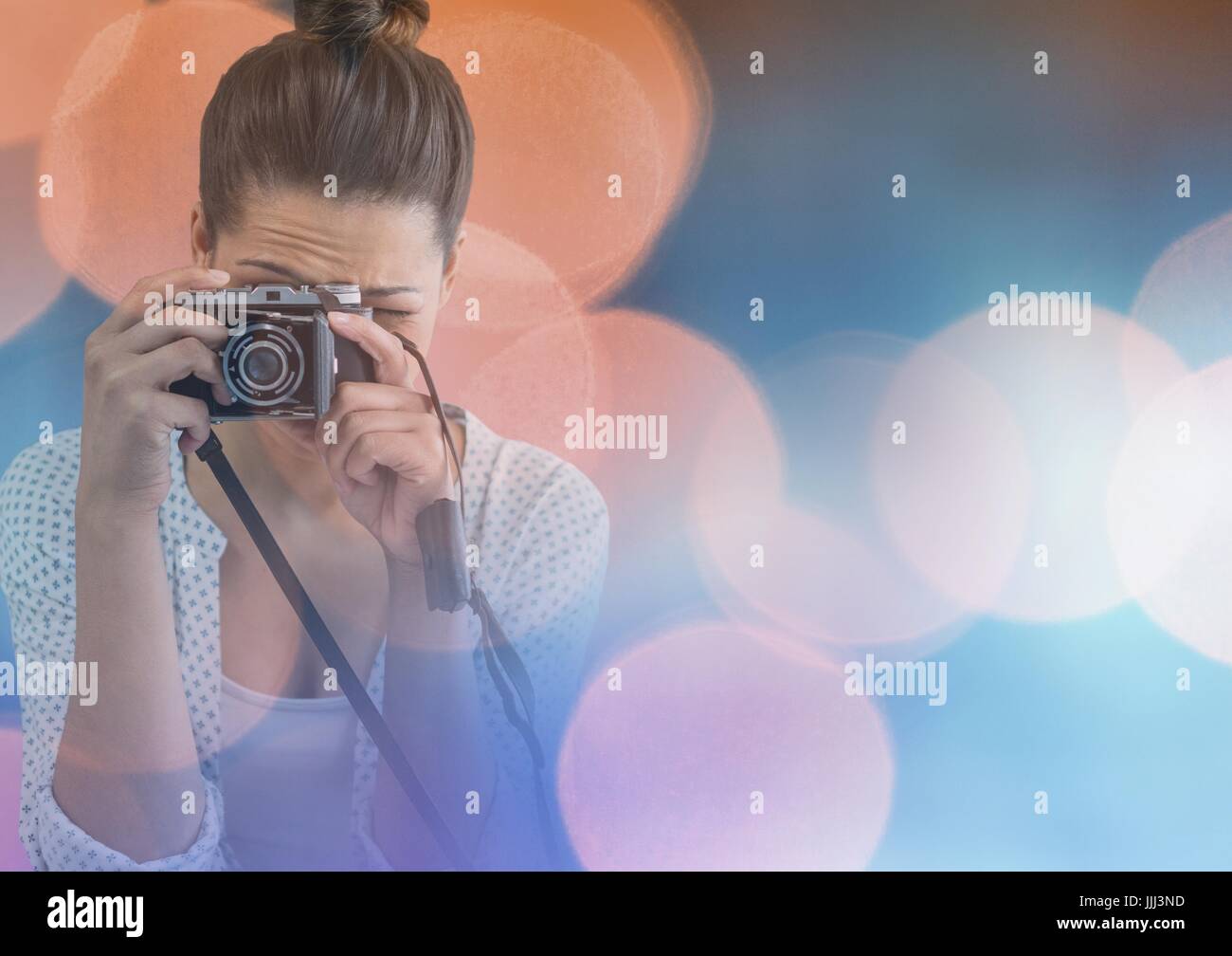 Pretty photographer taking picture in colored lights background Stock