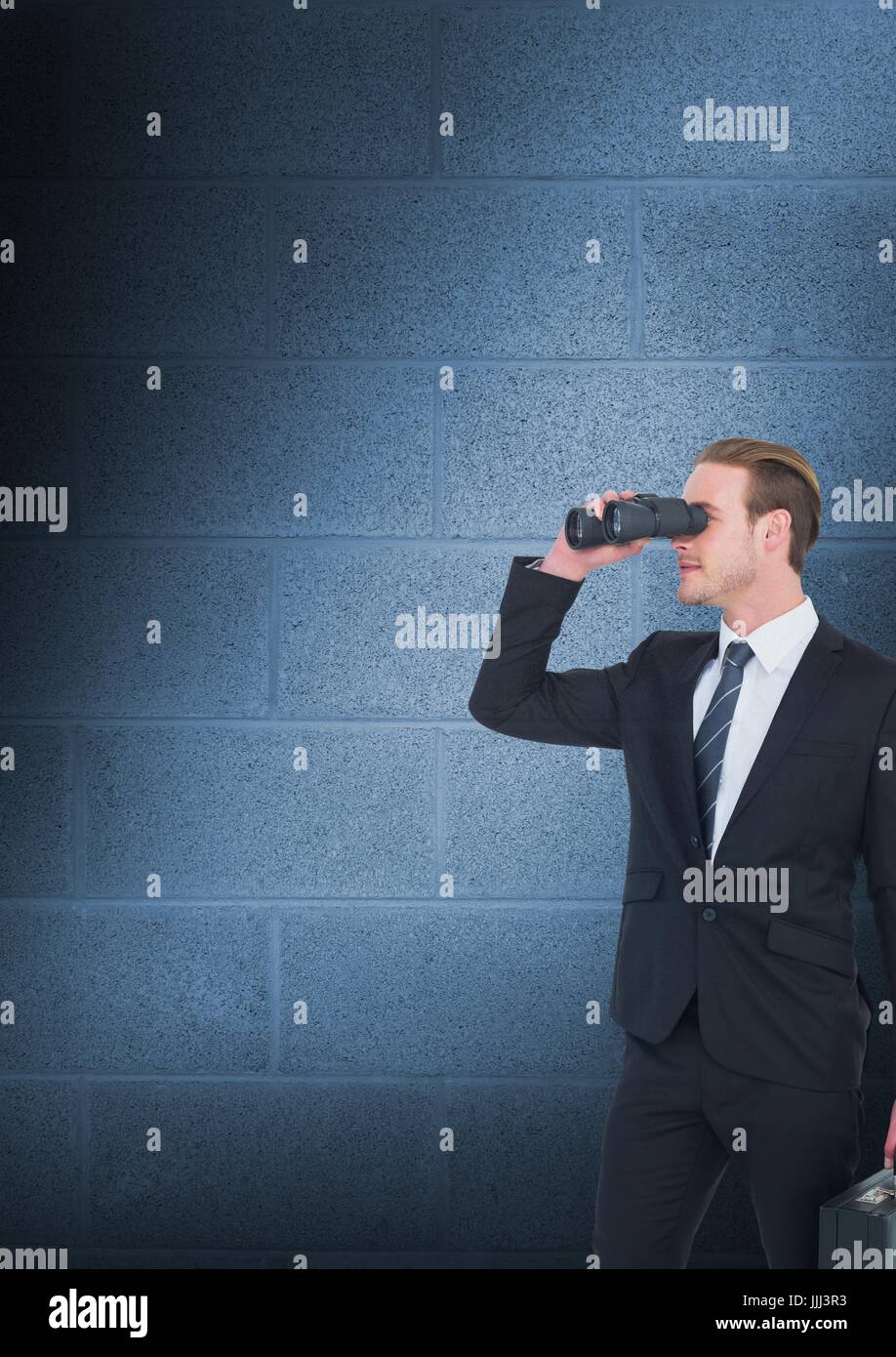 Man looking through binoculars against blue copy space wall Stock Photo