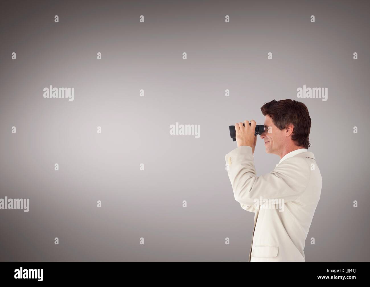 Man looking through binoculars against brown background and copy space Stock Photo