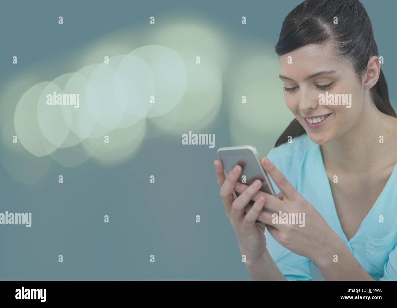Smiling woman texting with colored lights in background Stock Photo