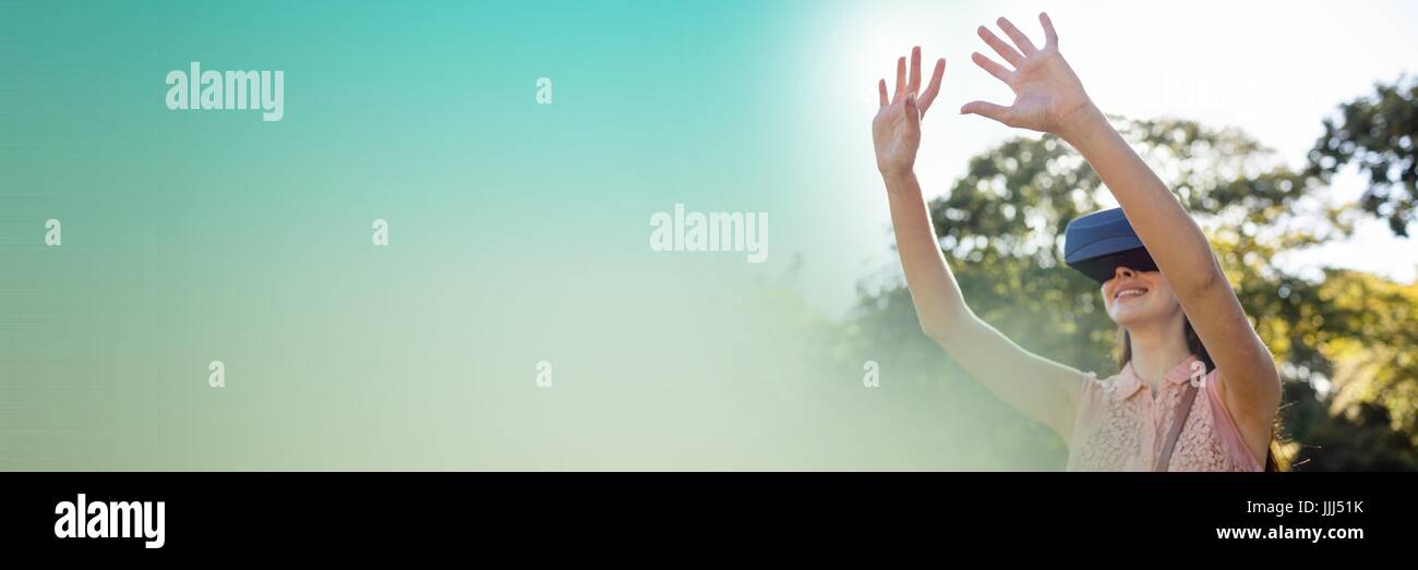 Woman in virtual reality headset outside with hands in air and green copy space transition Stock Photo