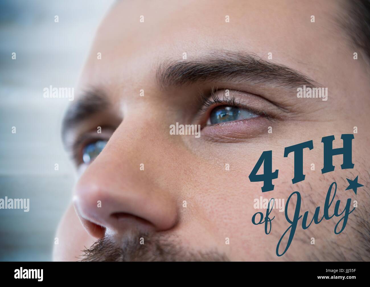 Close up of man's eyes with blue fourth of July graphic against blurry blue wood panel Stock Photo