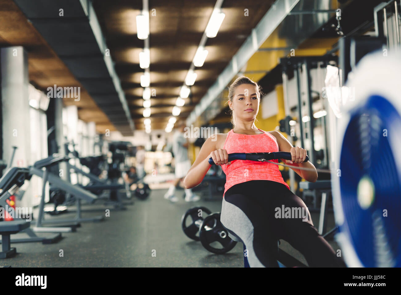 Young cute woman doing exercises with rowing machine Stock Photo