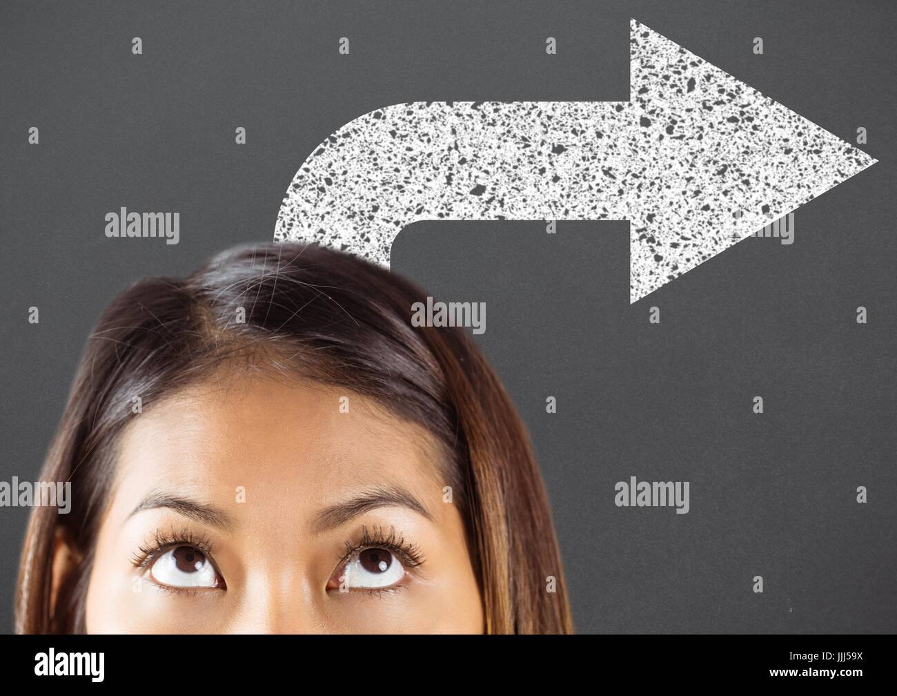 Top of woman's head looking up at white road arrow against grey background Stock Photo