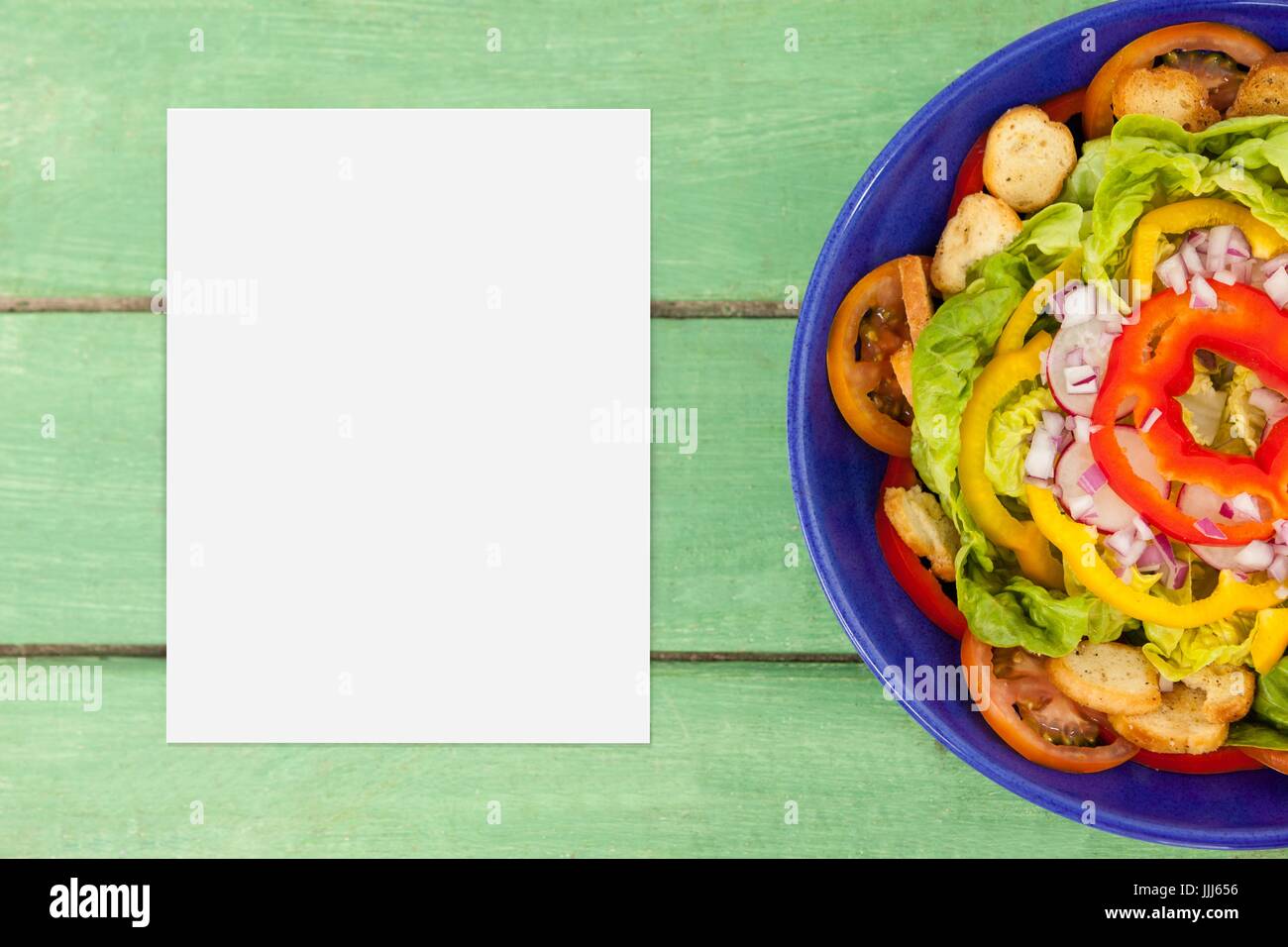 Blank card on green wooden desk with food and copy space on paper Stock Photo