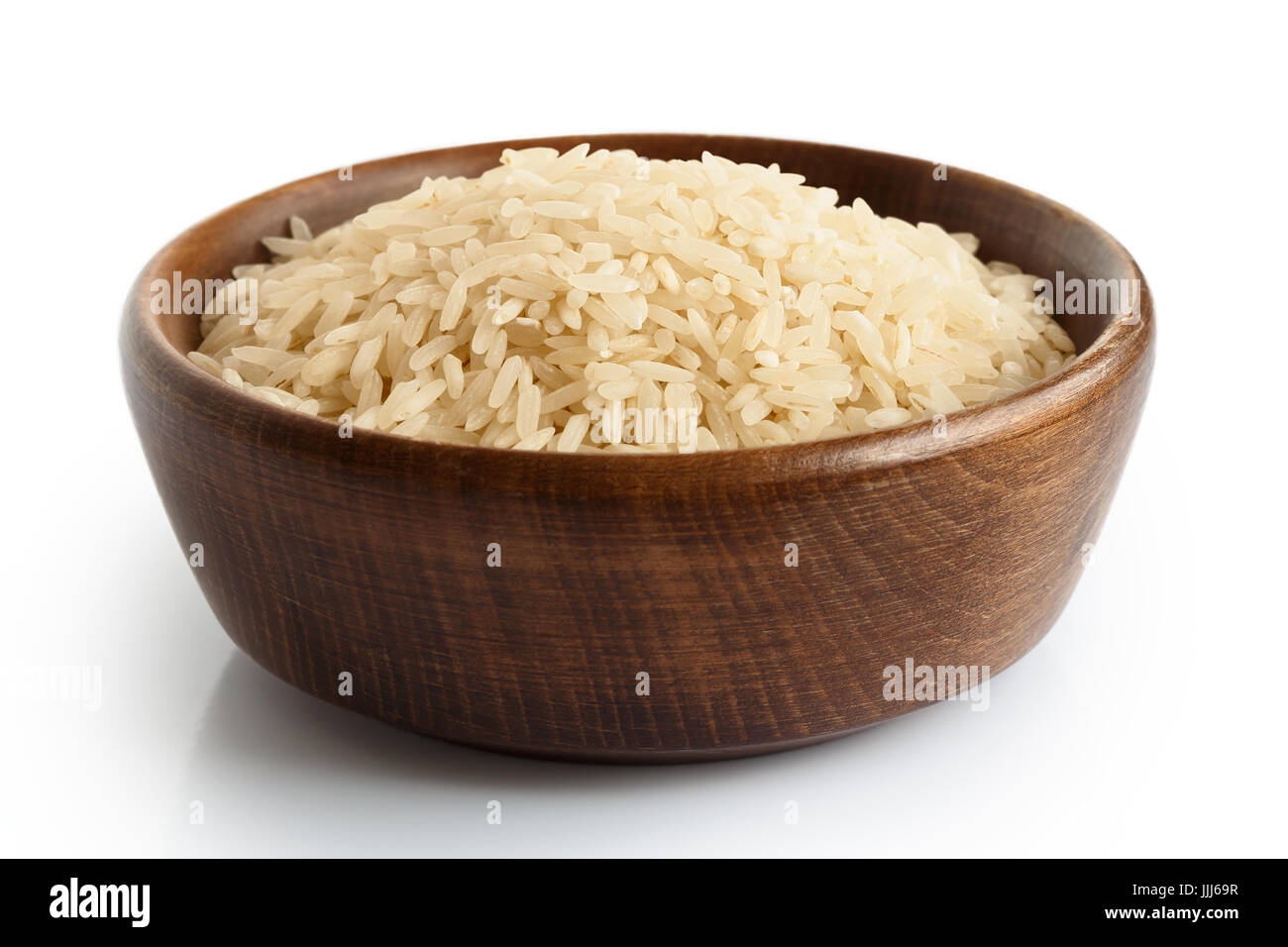 Uncooked long grain white rice  in dark wooden bowl isolated on white. Stock Photo