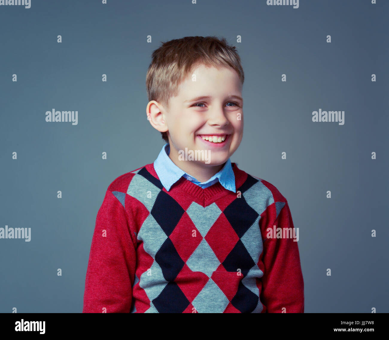 happy laughing child wearing a sweater  , isolated against grey background Stock Photo