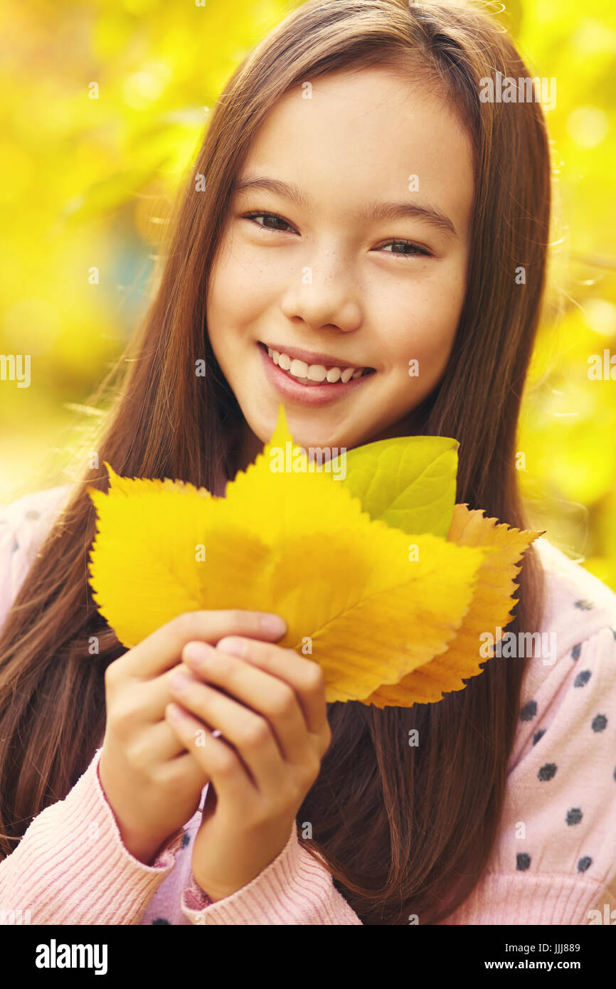 closeup portrait of a beautiful smiling teenage girl with yellow leaves ...