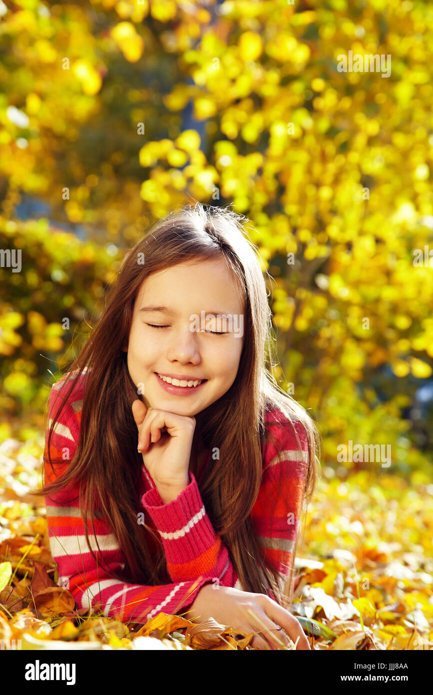 closeup portrait of a beautiful smiling teenage girl with yellow leaves ...