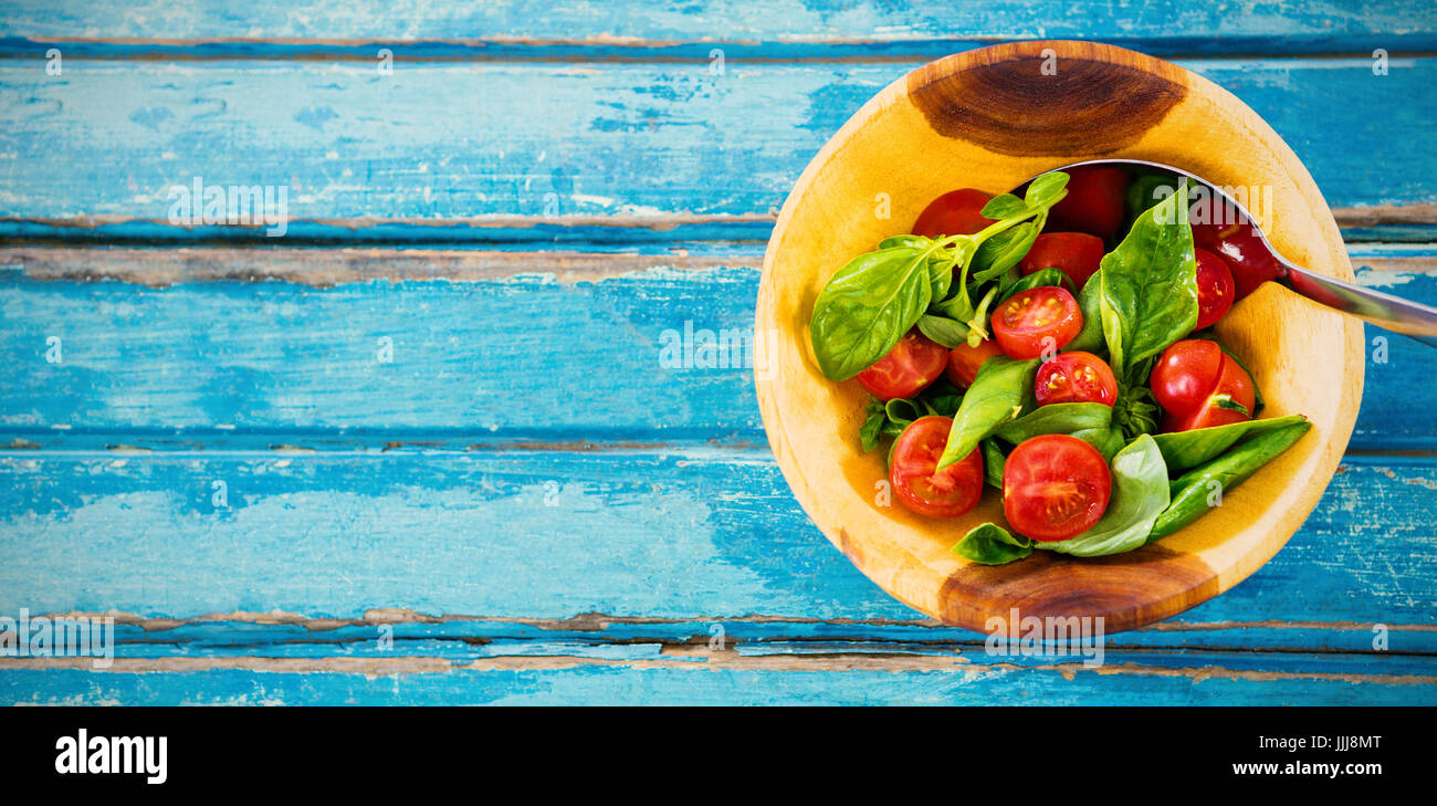 Fresh salad with spoon in wooden bowl on table Stock Photo