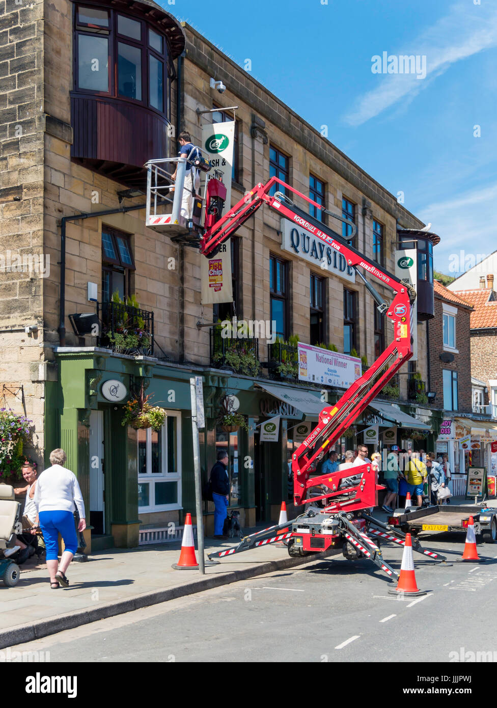 A decorator using an hydraulic access platform for painting the exterior of a café in Whitby Stock Photo